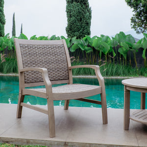 Wicker chair and table by a pool with greenery in the background