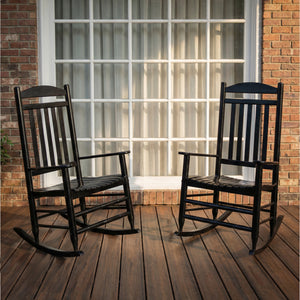Two black teak and mahogany rocking chairs on a wooden deck with a brick wall and large window in the background - Cambridge Casual