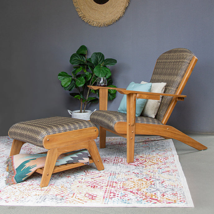 Wooden armchair and ottoman with patterned rug and plant in a room.