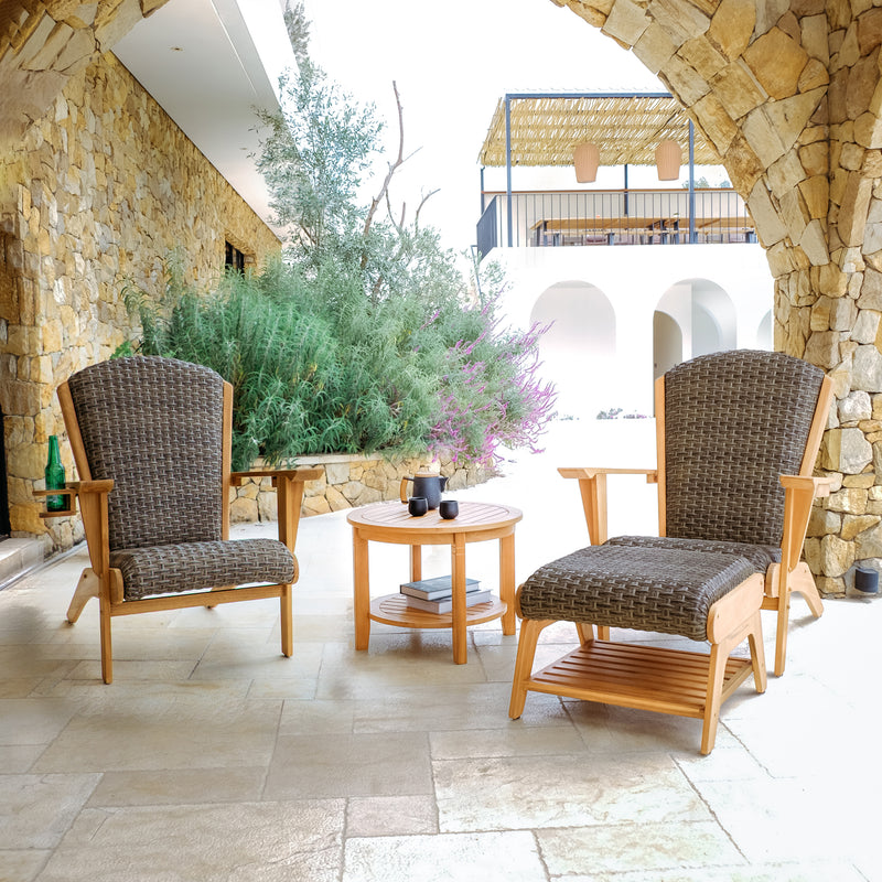 Two wicker chairs with cushions on a stone patio area.