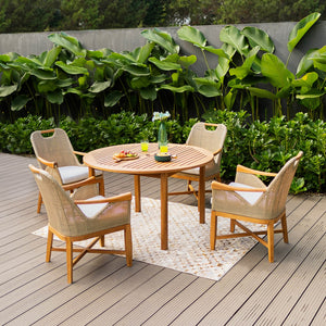 A sophisticated teak wood outdoor dining set with four armchairs and a round table, placed on a wooden deck with a lush green background.
